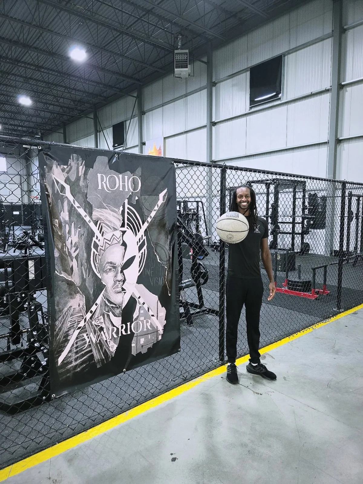 Coach with a basketball beside the ROHO Warrior banner